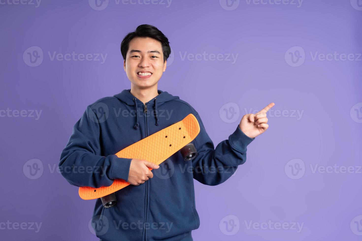image de Jeune asiatique homme en jouant planche à roulette sur violet Contexte photo