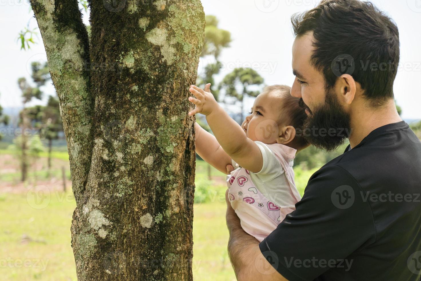 mignonne bébé étreindre une arbre tronc dans le printemps forêt. photo