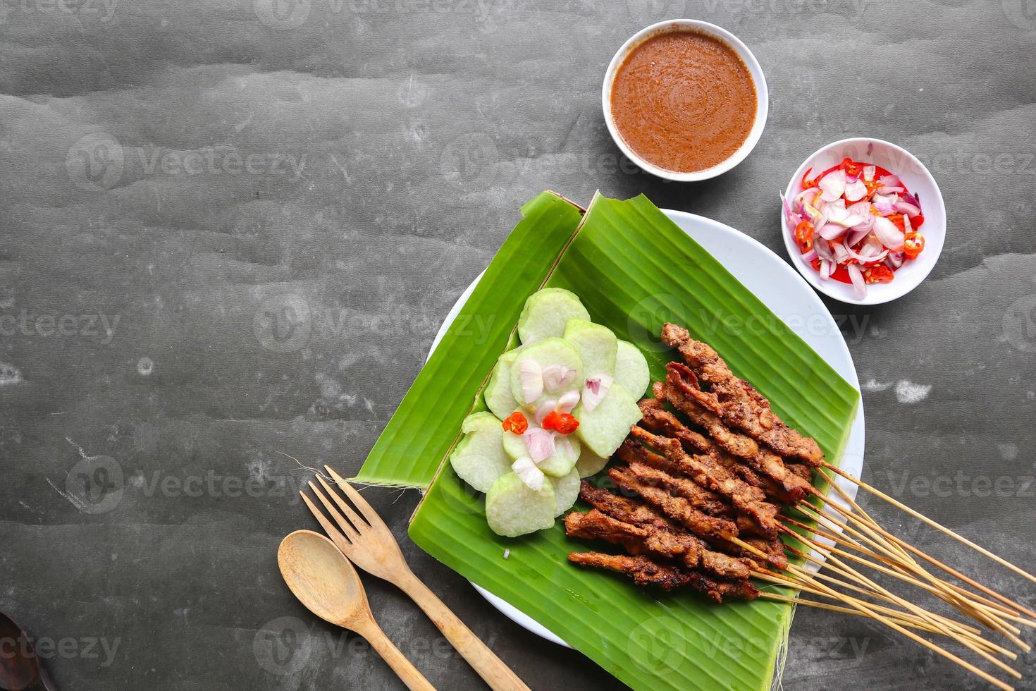 poulet satay ou poulet satay servi avec longtemps, riz gâteau et cacahuète sauce. servi sur banane laisser photo