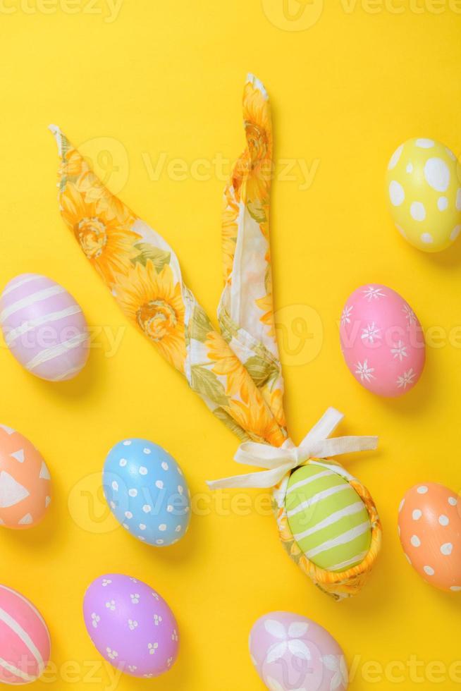 coloré peint Pâques Oeuf décoré avec une serviette de table dans le forme de une lapin sur une Jaune Contexte photo