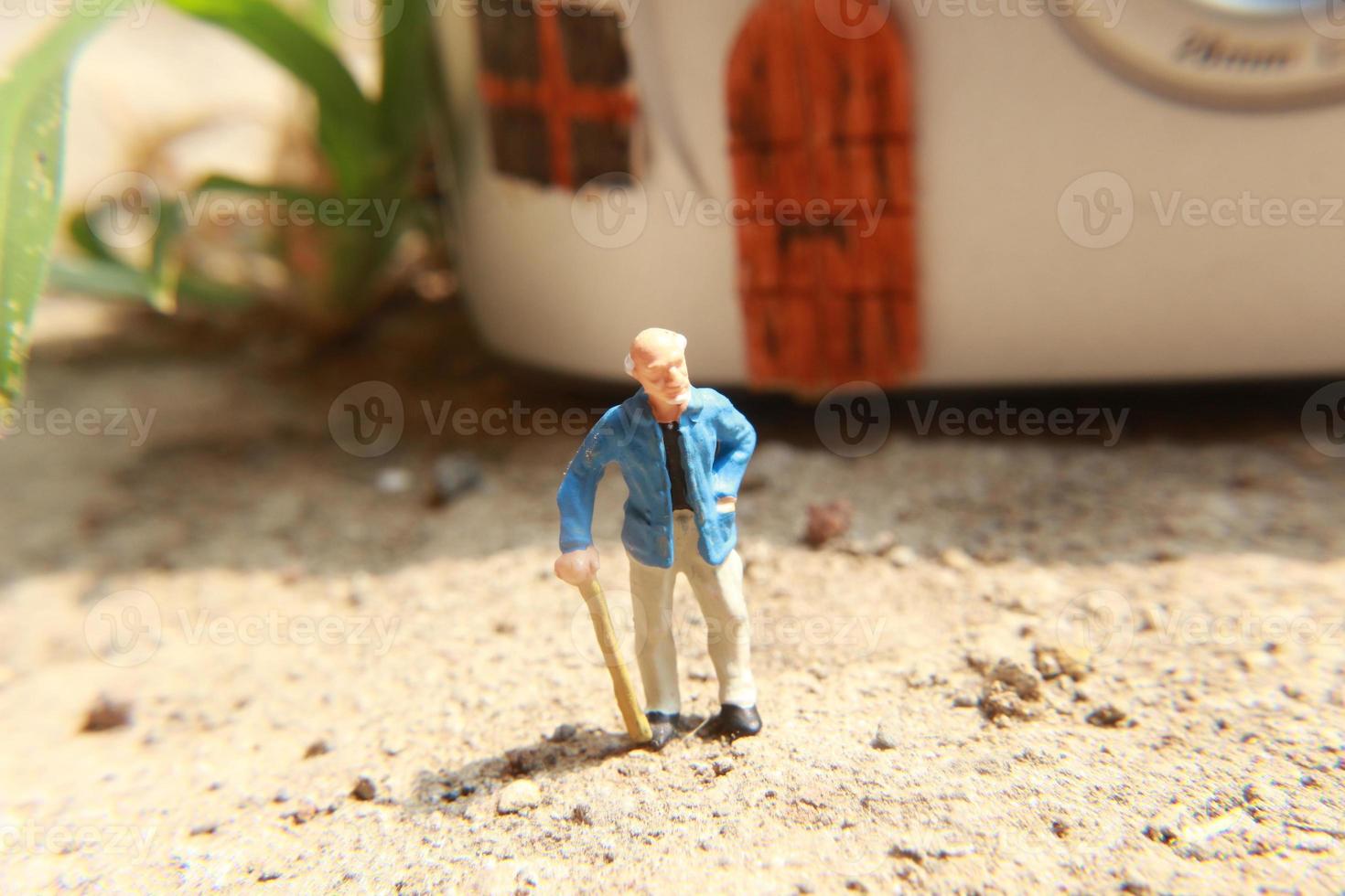 miniature figure de une grand-père qui est attendre dans de face de le maison. photo
