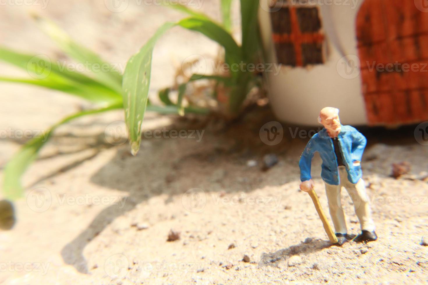 miniature figure de une grand-père qui est attendre dans de face de le maison. photo