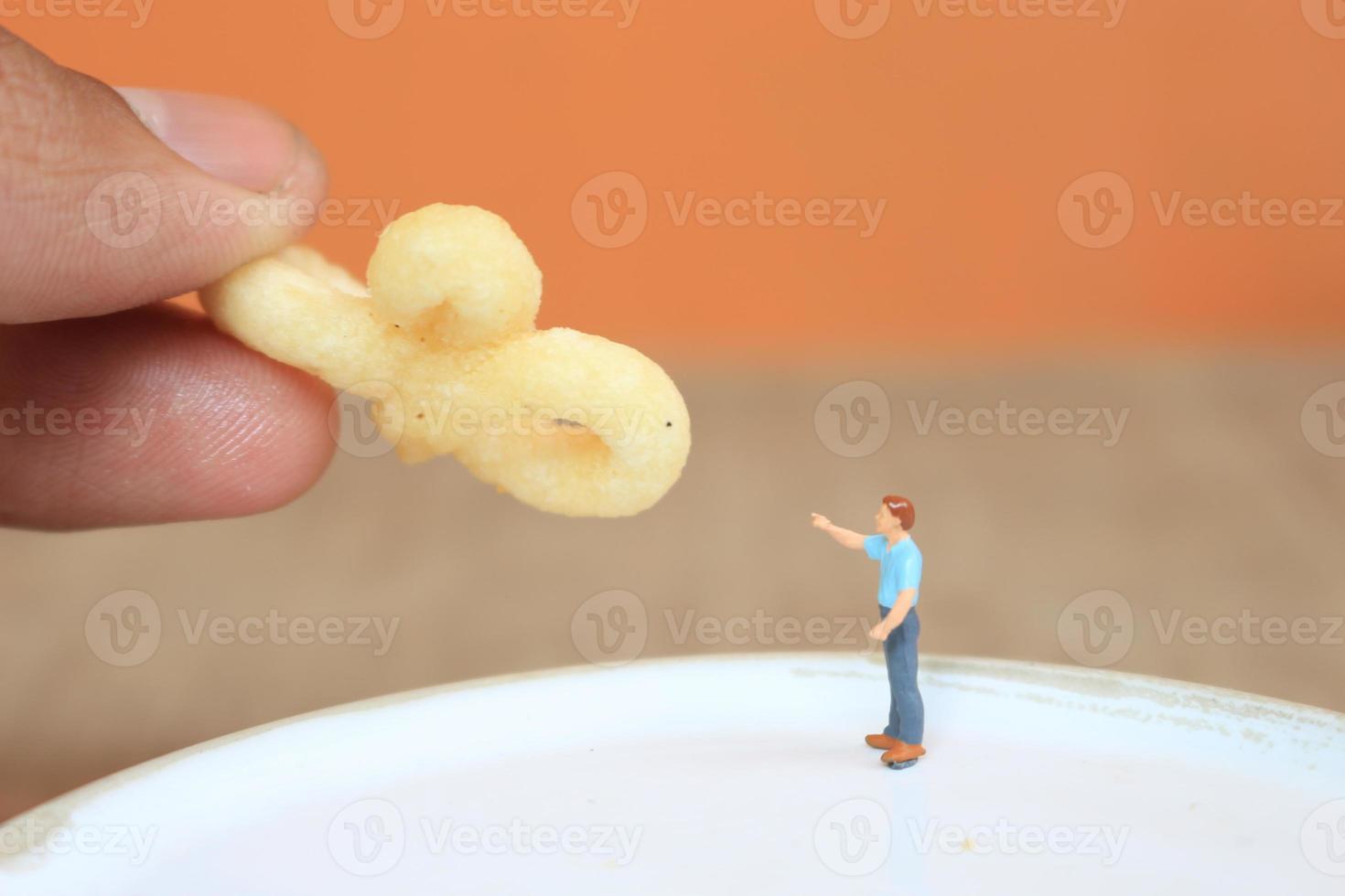 miniature figure de une enfant interagir avec Humain mains donnant aliments. photo