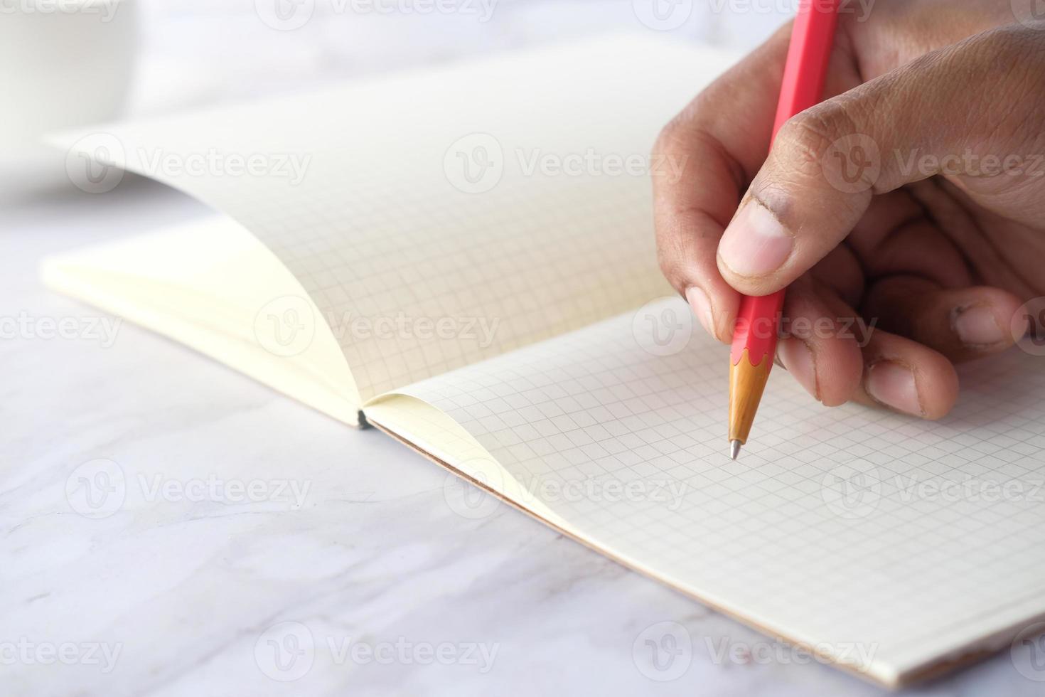 Gros plan de la main de l'homme écrit avec un crayon sur papier à lettres graphique photo