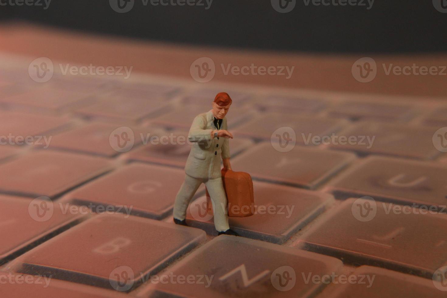 une miniature figure de un Bureau ouvrier porter une mallette en marchant entre le claviers. photo