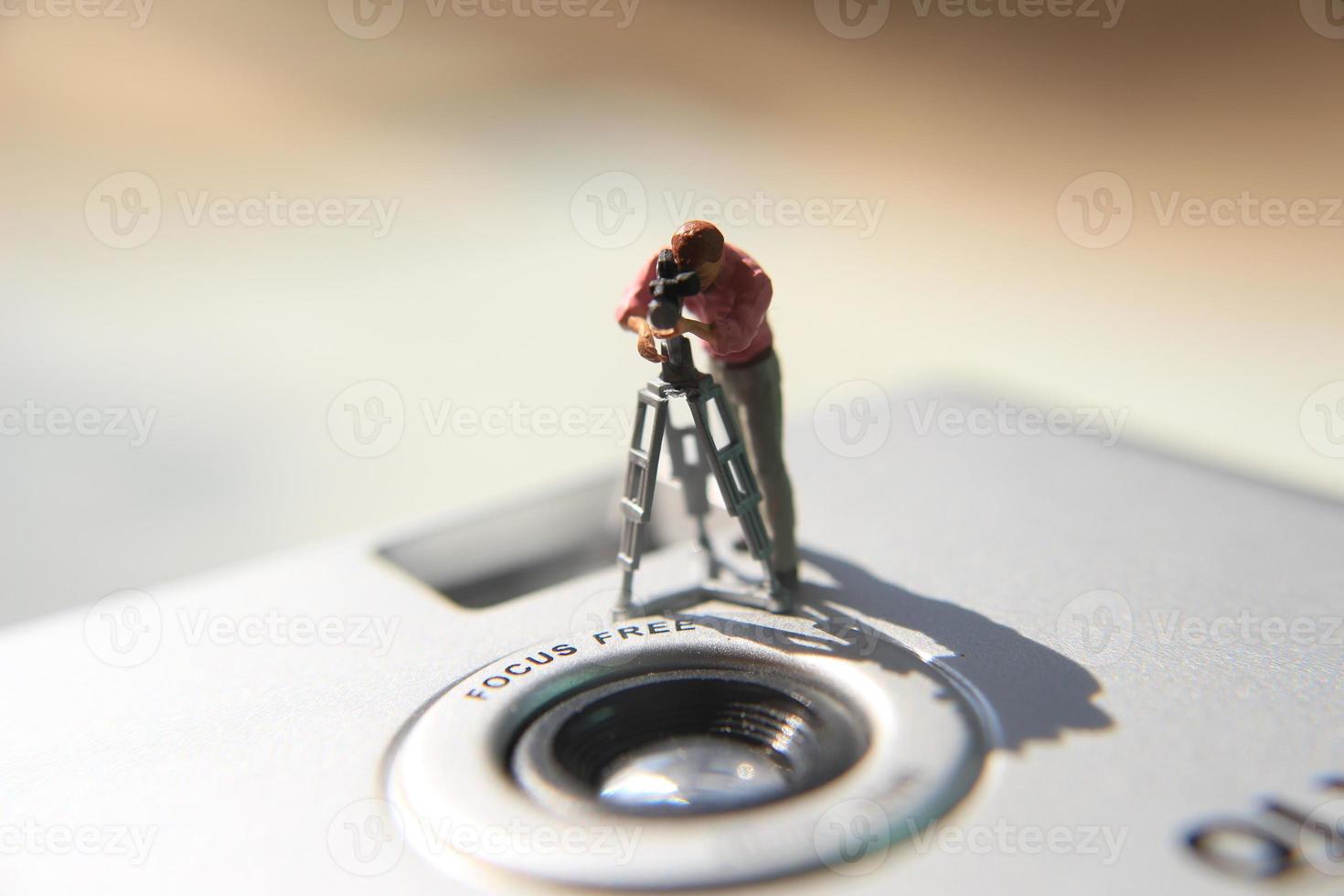 miniature figure de une vidéaste enregistrement sur un analogique caméra. photo