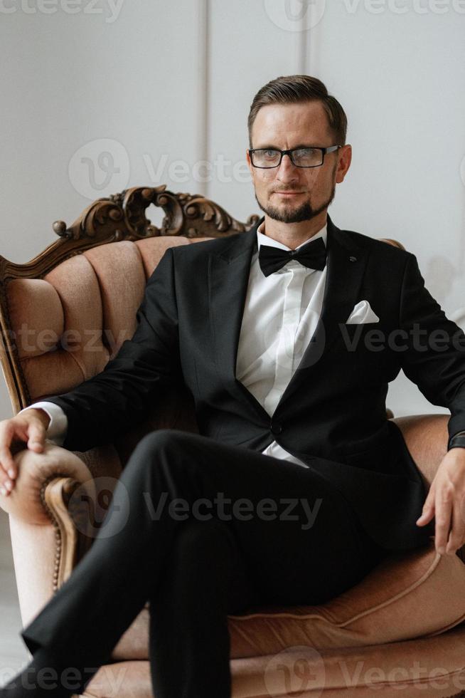 portrait de une jeune marié dans une noir costume et des lunettes dans une studio photo