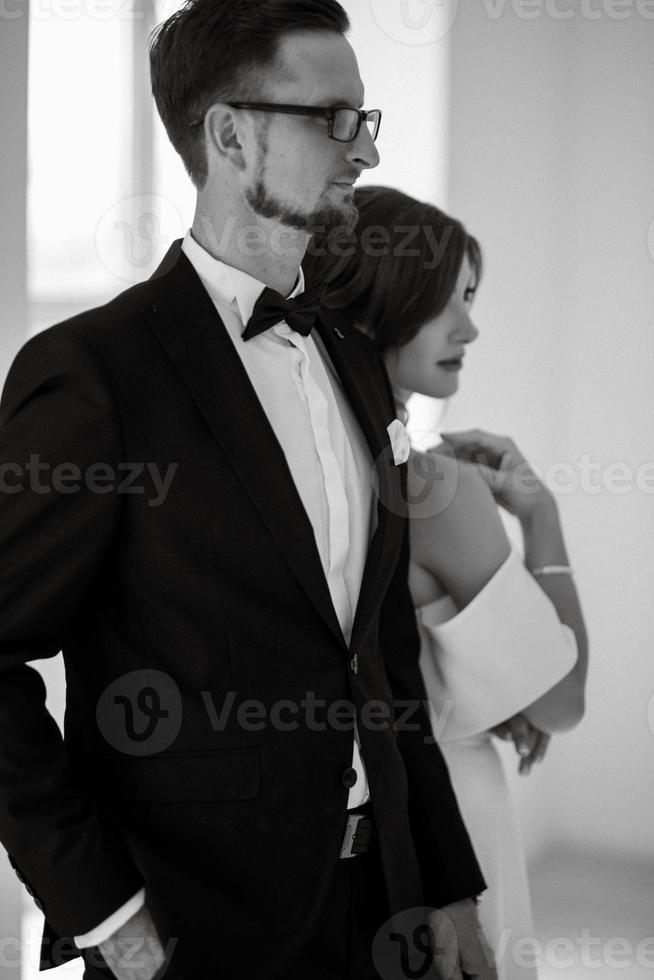 jeune marié dans une noir costume attacher et le la mariée dans une brillant studio photo