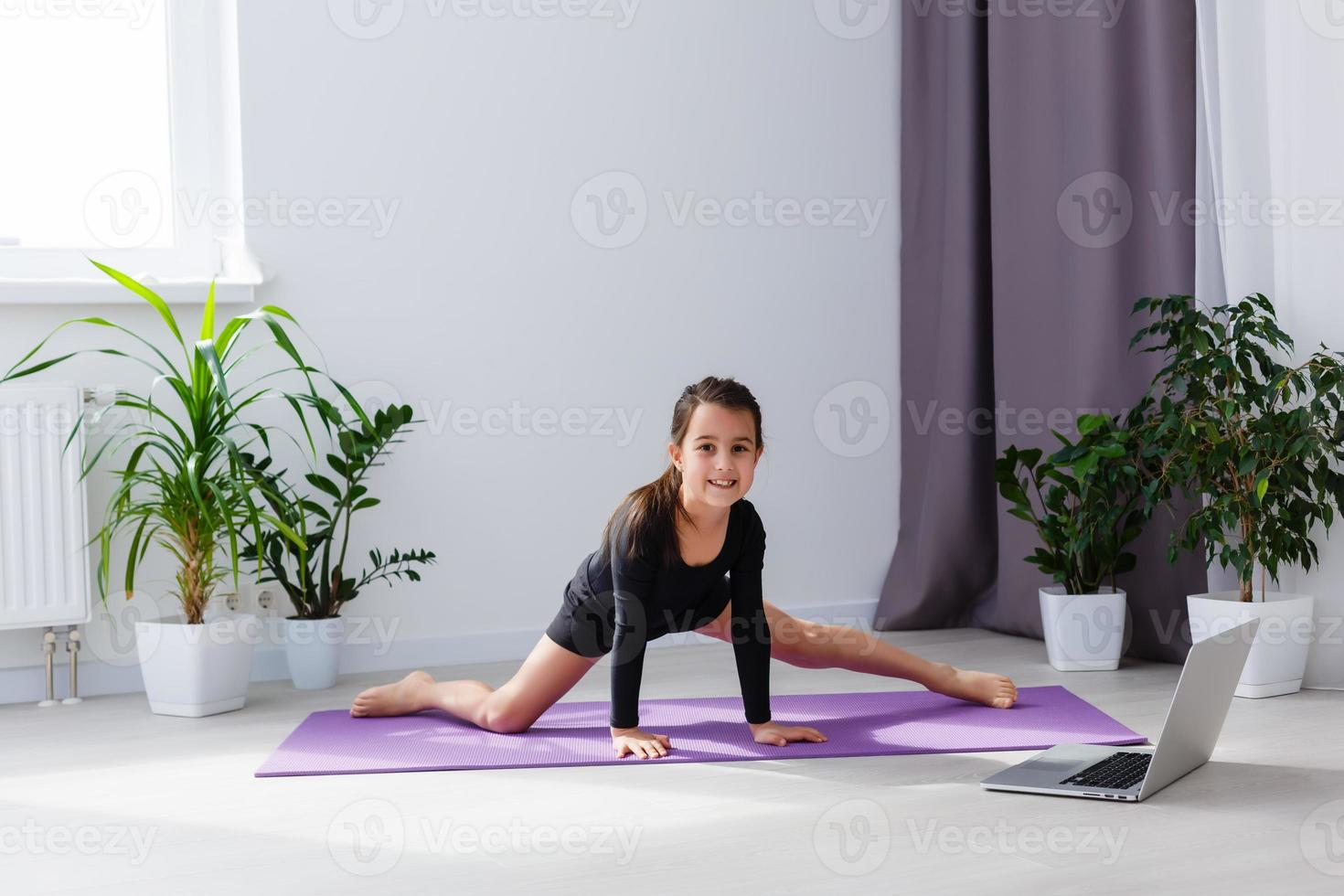 seul fille Faire yoga des exercices en ligne sur portable sur le sol dans le lumière chambre, rester Accueil sûr monde. photo