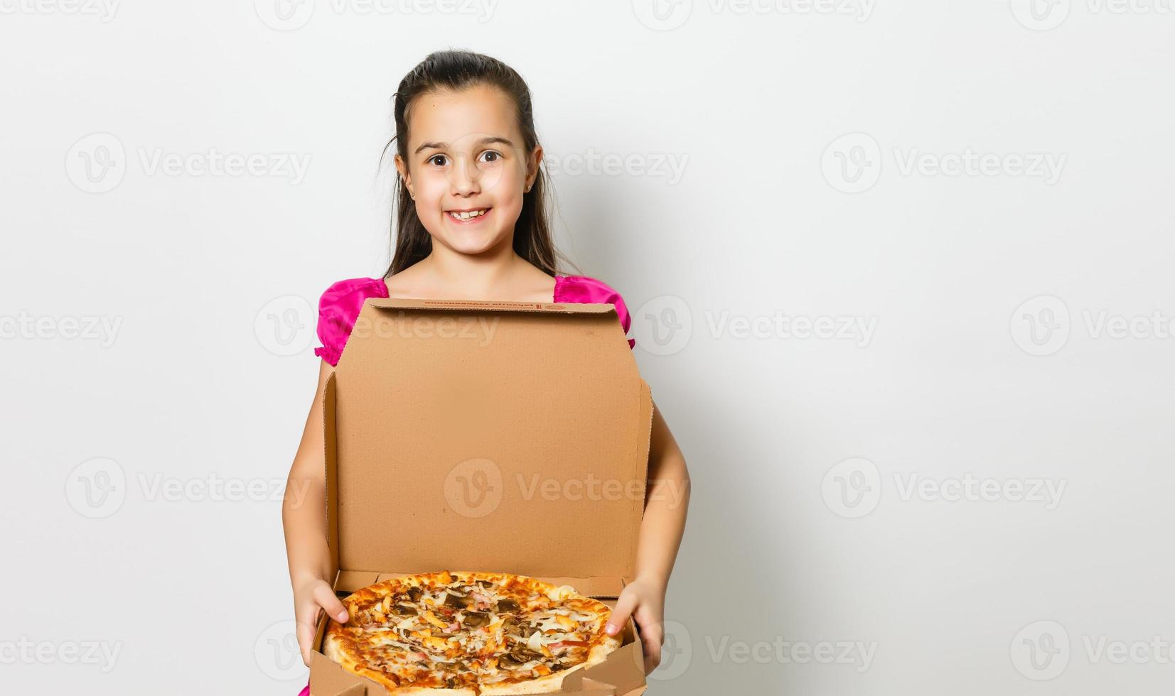 mignonne peu Indien asiatique fille enfant en mangeant savoureux Pizza dans boîte. permanent isolé plus de blanc Contexte. photo