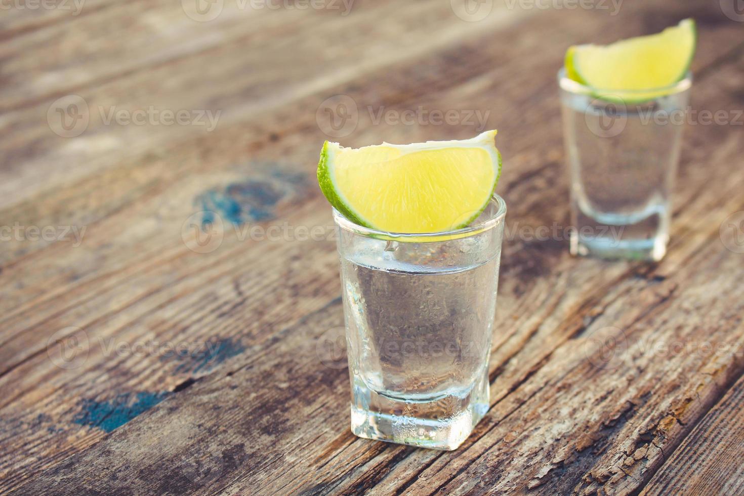 Vodka et citron vert tranches sur en bois Contexte. photo