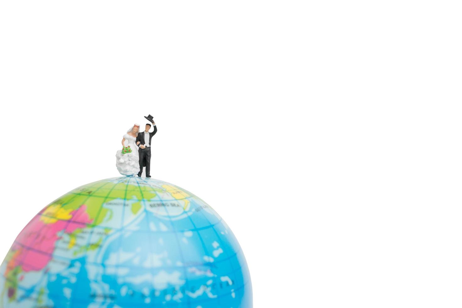 Mariage miniature, couple de mariés sur un globe sur fond blanc photo