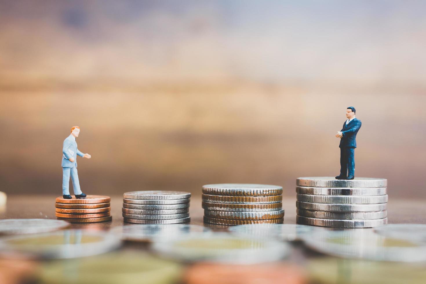 Hommes d'affaires miniatures debout sur de l'argent avec un fond en bois photo