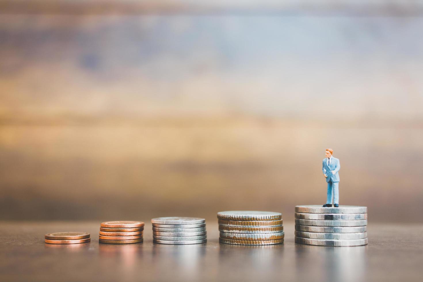 Hommes d'affaires miniatures debout sur de l'argent avec un fond en bois photo