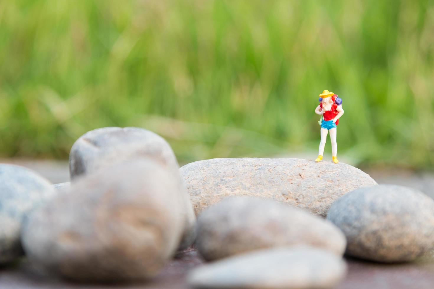 Voyageur miniature avec un sac à dos debout et marchant dans un pré photo