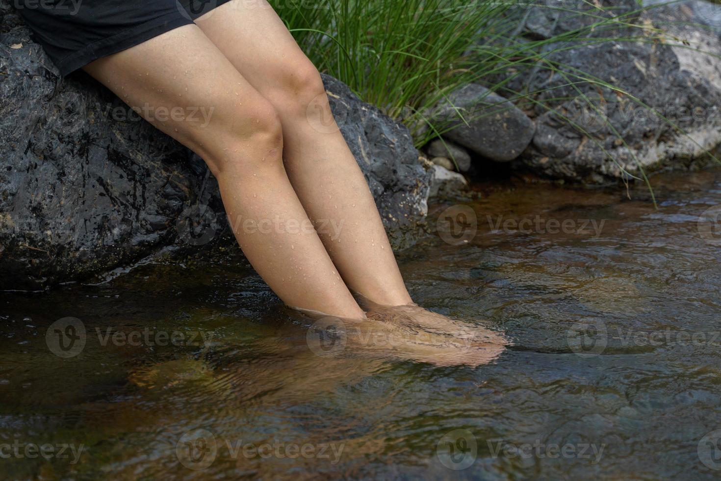 asiatique femme trempage pieds dans l'eau à ressentir rafraîchi et détendu prendre plaisir la nature avec des arbres, ruisseaux, montagnes et Frais air à le nationale parc. doux et sélectif se concentrer. photo