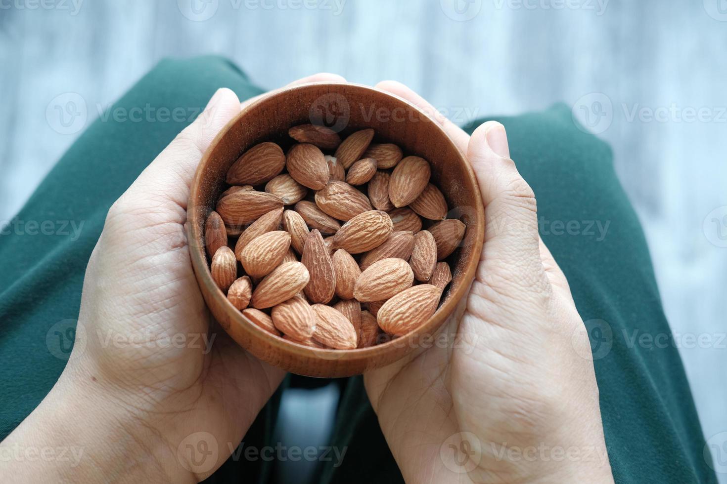 bouchent les mains tenant un bol sur les amandes photo