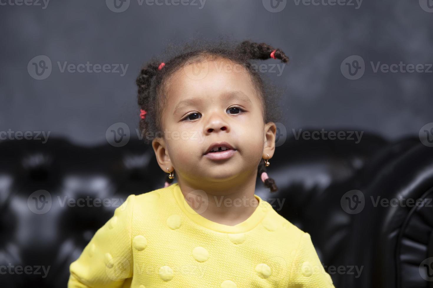 portrait de une peu espiègle africain américain fille sur une foncé Contexte. photo