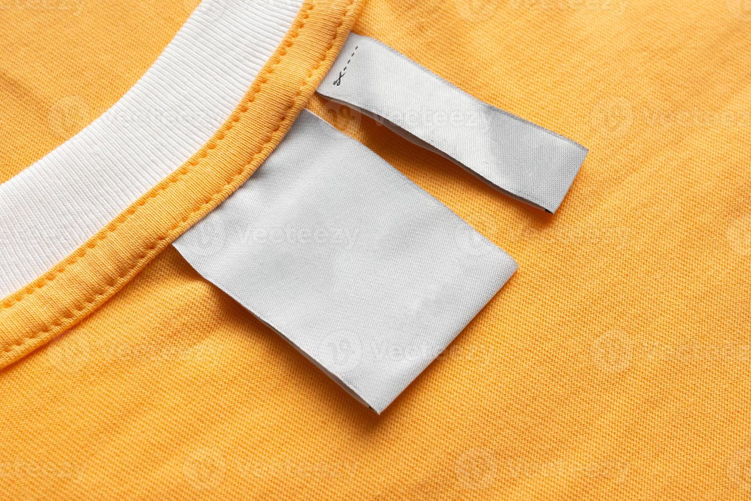 étiquette de vêtements de soin de lessive blanche vierge sur fond de texture de tissu jaune photo