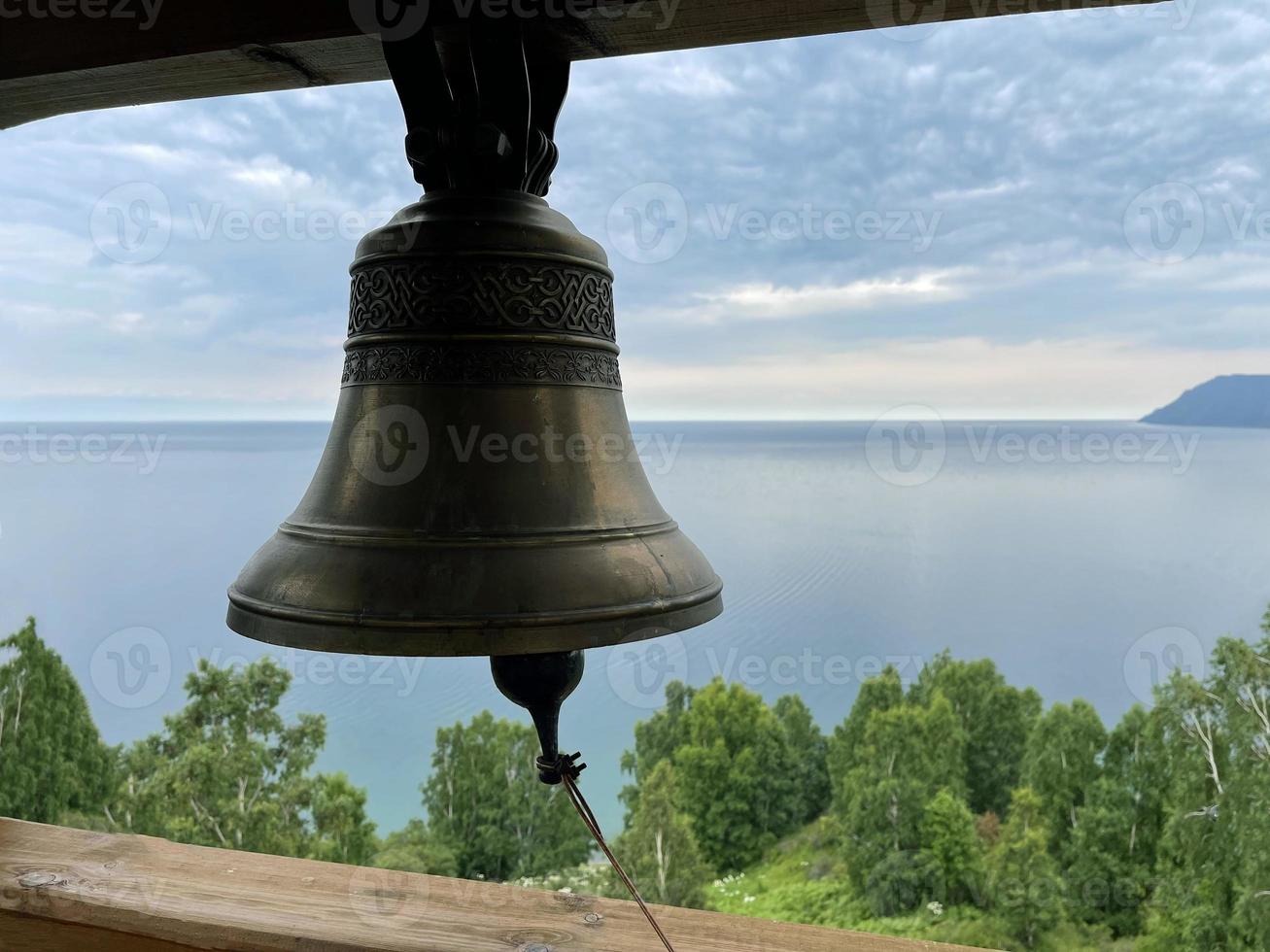 cloche dans le beffroi de une Christian église contre le toile de fond de Lac baïkal, Russie photo
