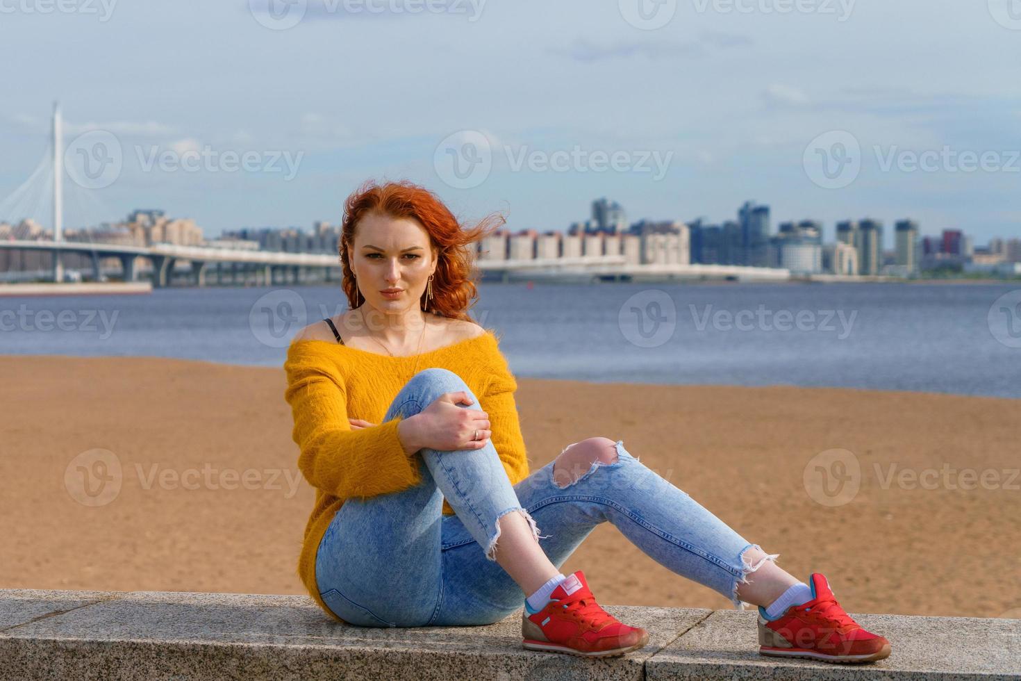 Jeune roux fille dans Jaune chandail et jeans. jolie femme est assis photo