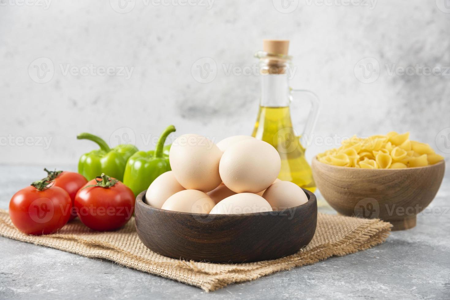 œufs de poule crus avec une bouteille en verre d'huile et de légumes frais photo