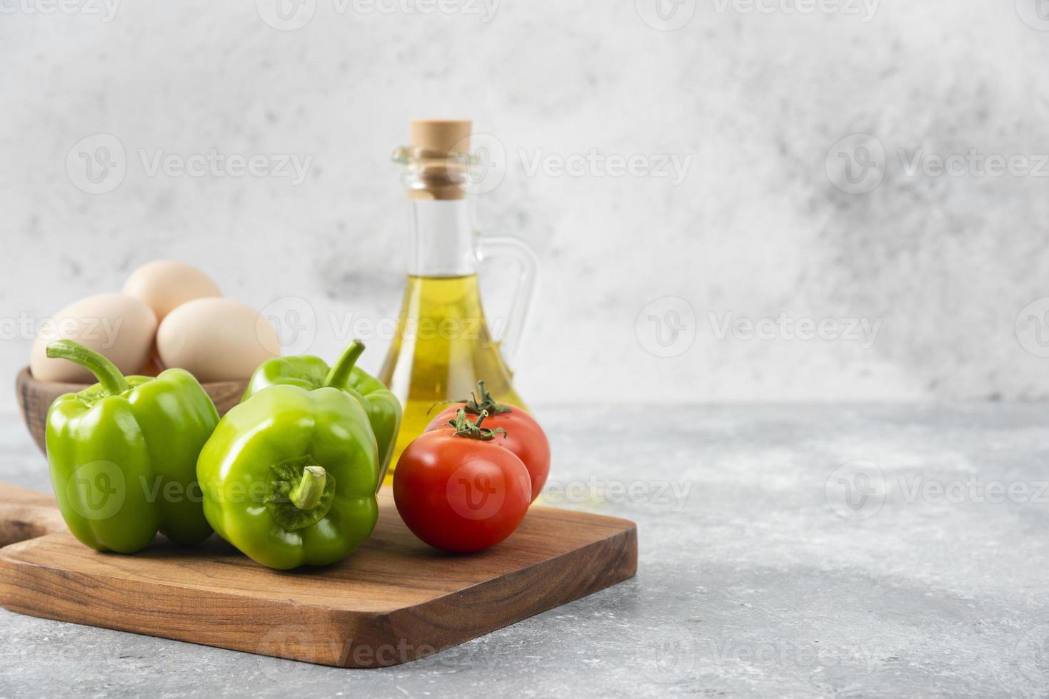 œufs de poule crus avec une bouteille en verre d'huile et de légumes frais photo