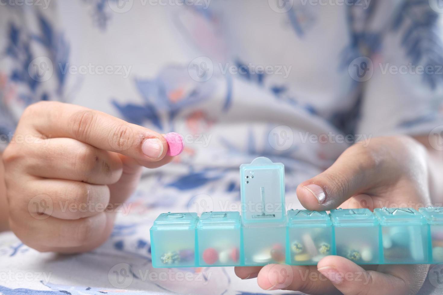 mains de femmes prenant des médicaments dans une boîte à pilules photo