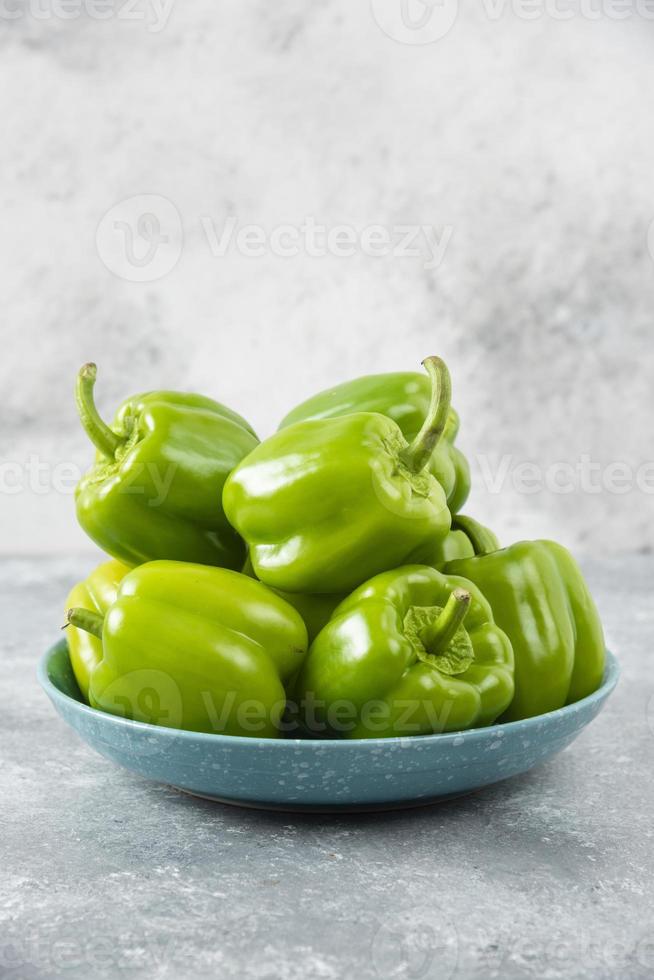 Poivrons verts frais placés sur une plaque bleue sur une table en pierre photo