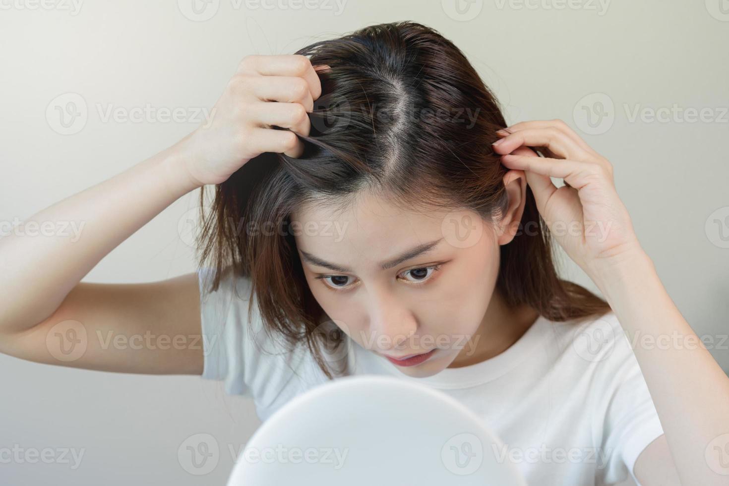 endommagé cheveux, visage sérieux asiatique Jeune femme inquiéter à la recherche à cuir chevelu dans miroir, main dans Pause dans de face cheveux perte, mince problème symptôme à maison. santé se soucier shampooing beauté, isolé sur Contexte. photo