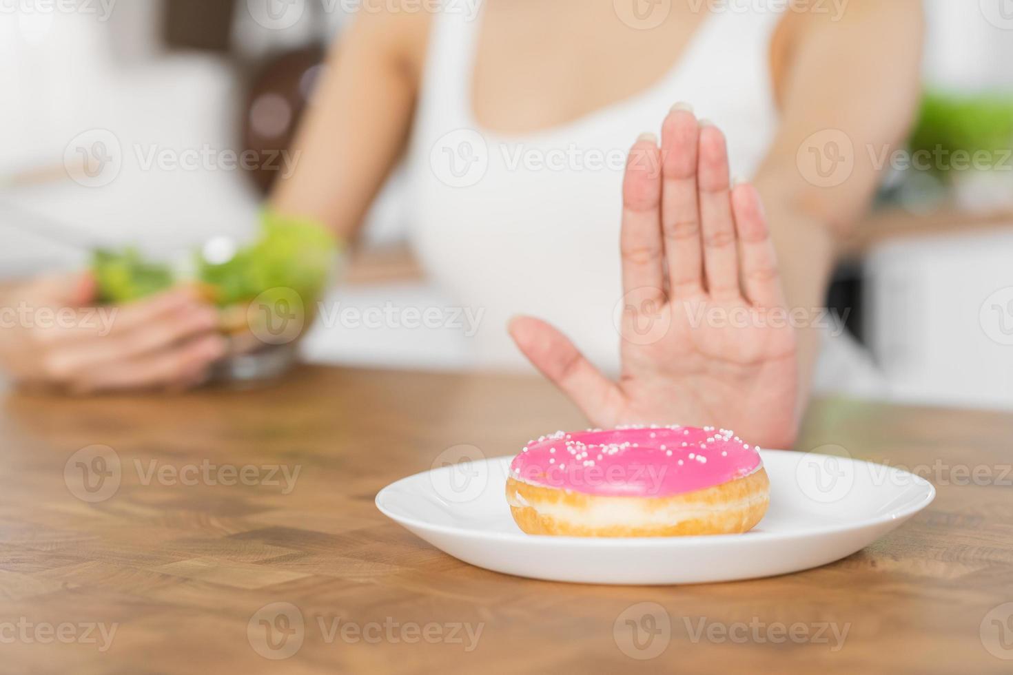 régime, suivre un régime asiatique Jeune femme ou fille utilisation main pousser dehors, Nier sucré Donut et choisir tomate, mélanger salade légumes, manger nourriture pour bien en bonne santé, santé lorsque affamé. proche en haut femelle poids perte personne. photo