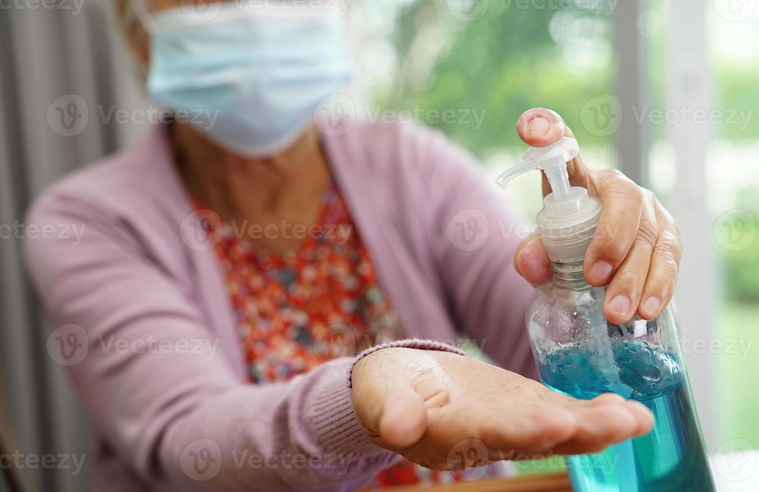 femme senior asiatique presse gel désinfectant à l'alcool bleu pour se laver les mains protéger l'infection coronavirus. photo