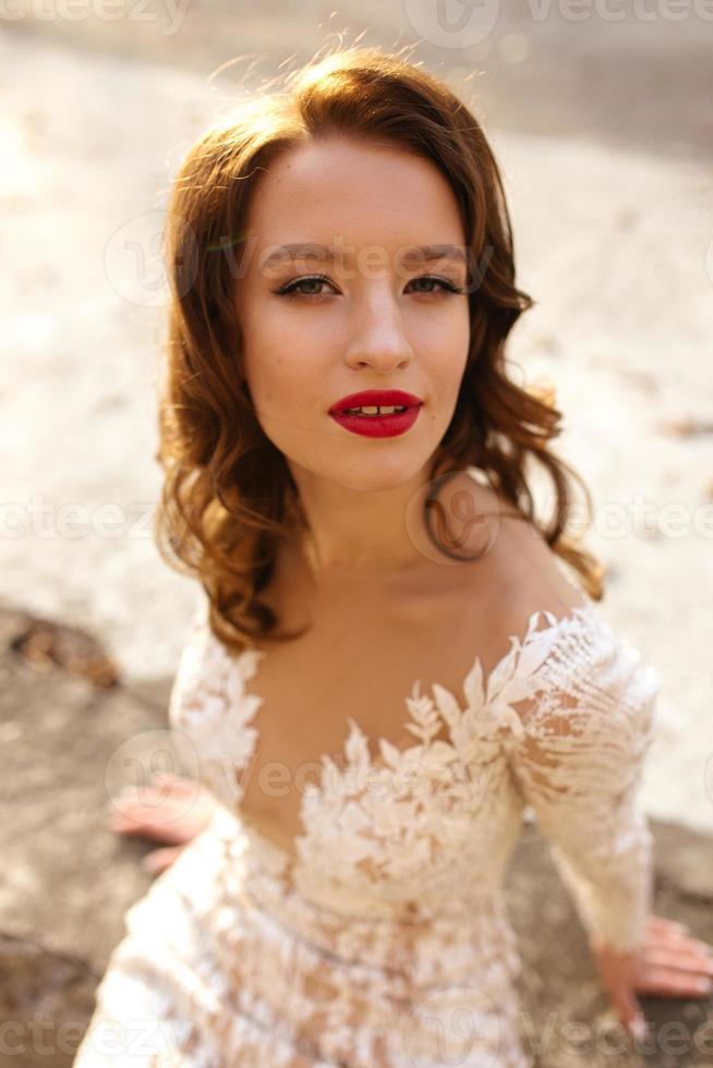 beauté portrait de une magnifique blond la mariée dans voile avec une bouquet de fleurs dans le sien mains sur une gris Contexte. photo