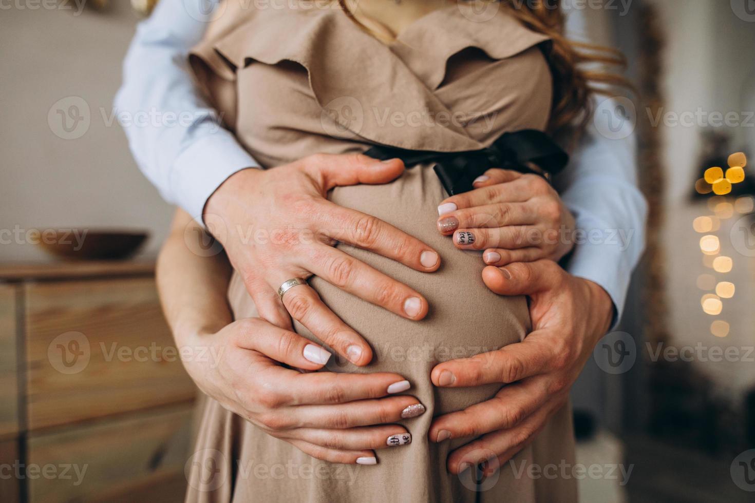 les mains de l'homme embrassent le ventre de la femme enceinte photo