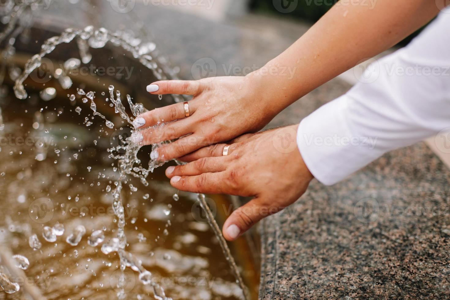 mains avec l'eau éclaboussure, rétro-éclairé par le soir Soleil. photo