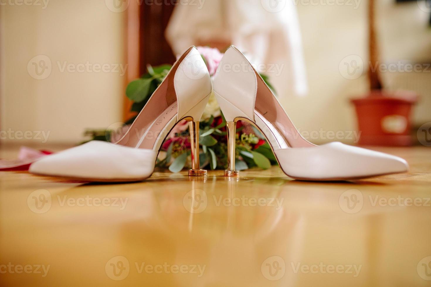 femelle pieds dans blanc mariage des sandales avec une bouquet de camomille photo