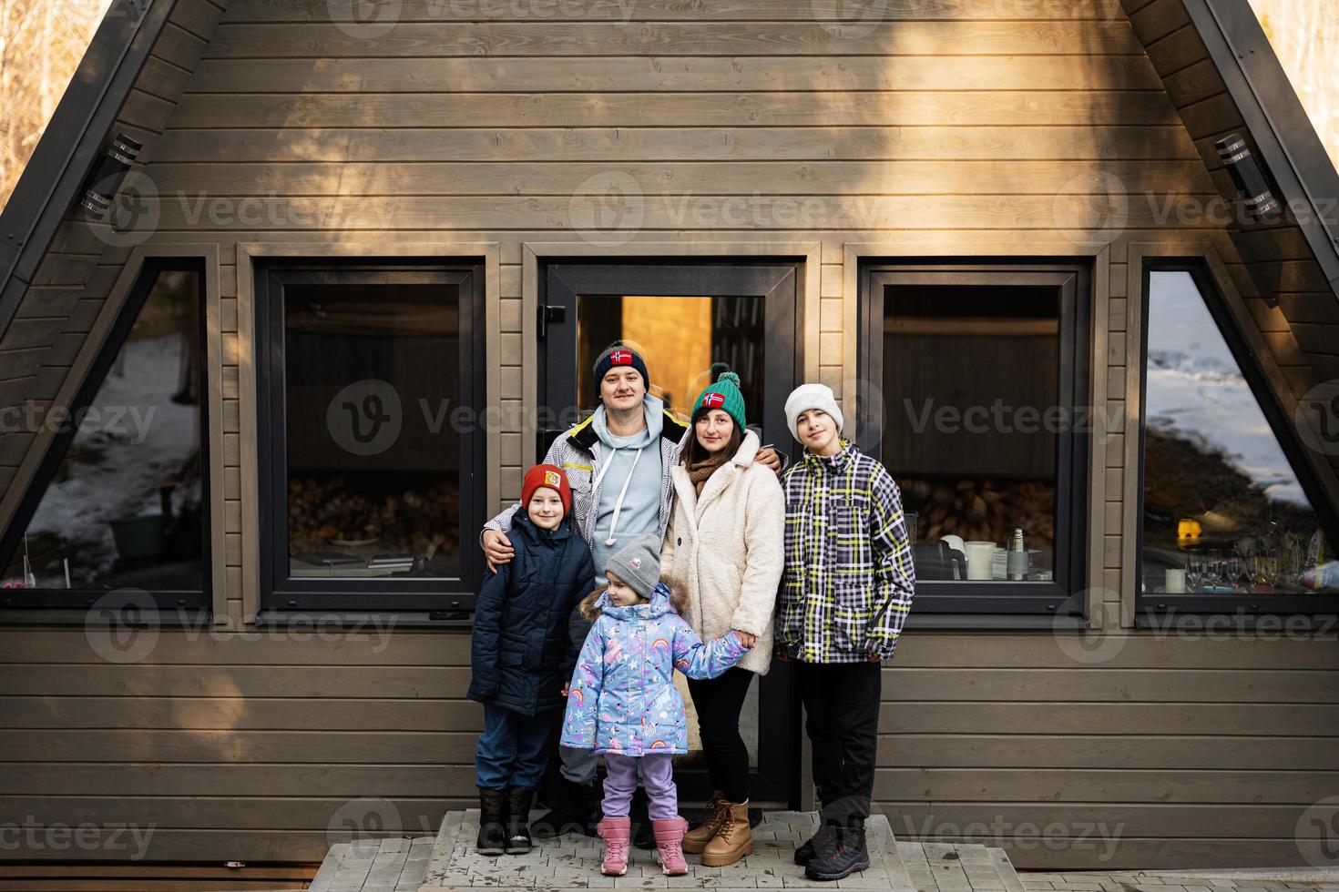 famille avec Trois des gamins contre en bois cabine minuscule maison. les enfants dans campagne. photo