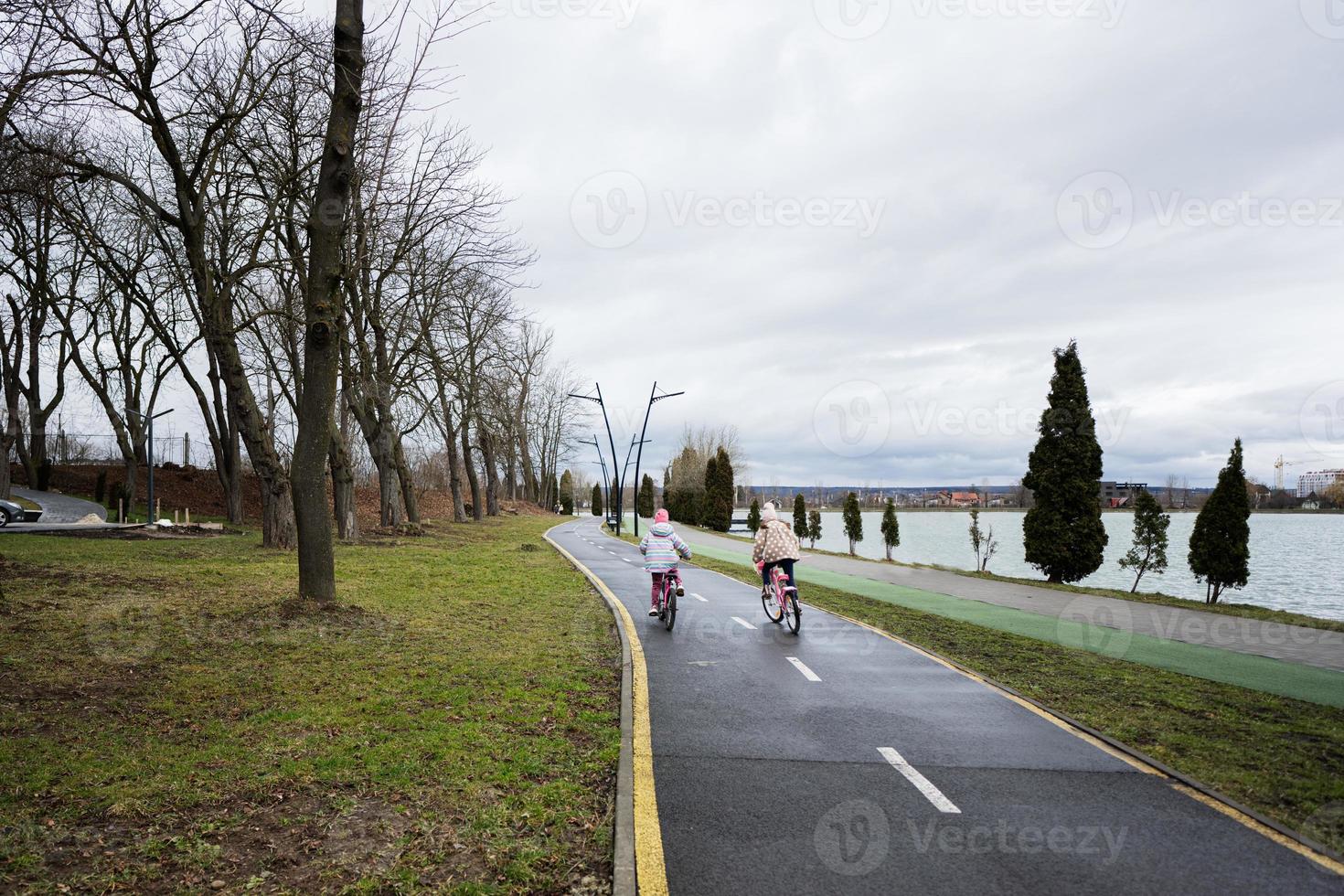 deux les filles cyclisme sur cycle chemin le long de le ville ruelle. photo