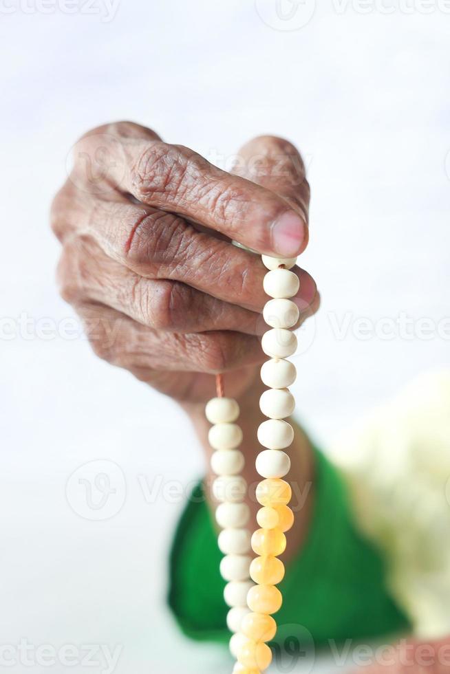 Close up of senior woman's hand priant avec des perles photo