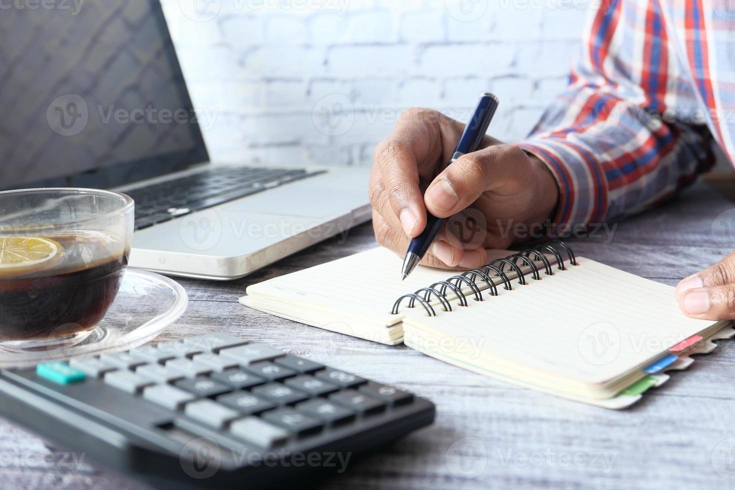 Gros plan de la main de l'homme écrit dans un bloc-notes photo