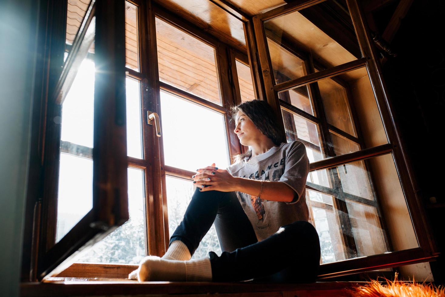 fille dans une maison près de la fenêtre donnant sur un paysage enneigé photo