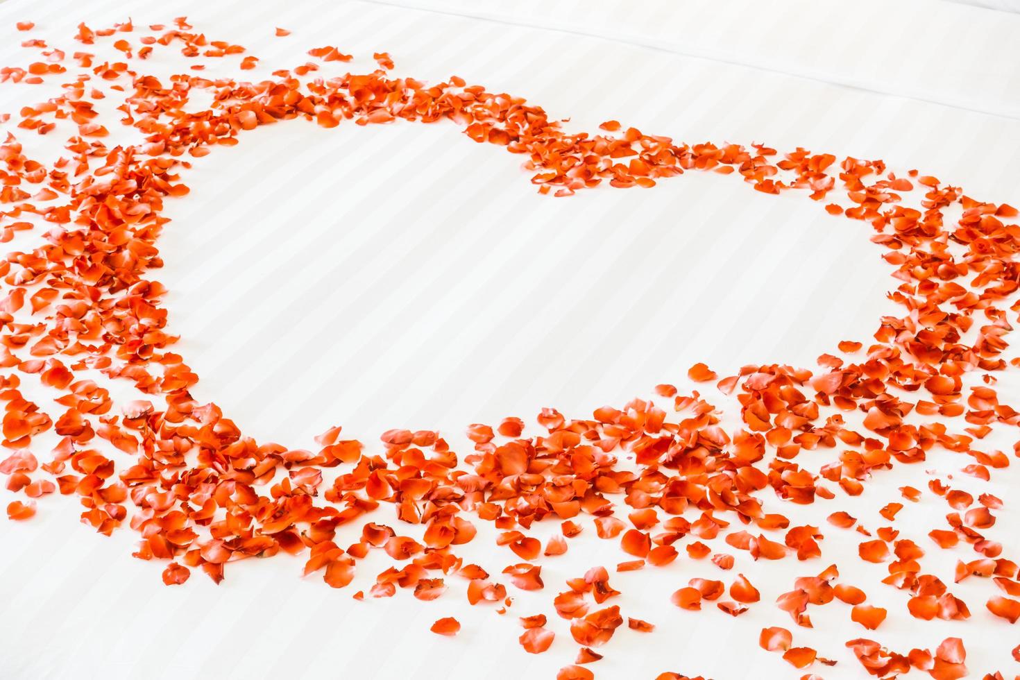 coeur rouge fait de pétales de fleurs sur le lit photo
