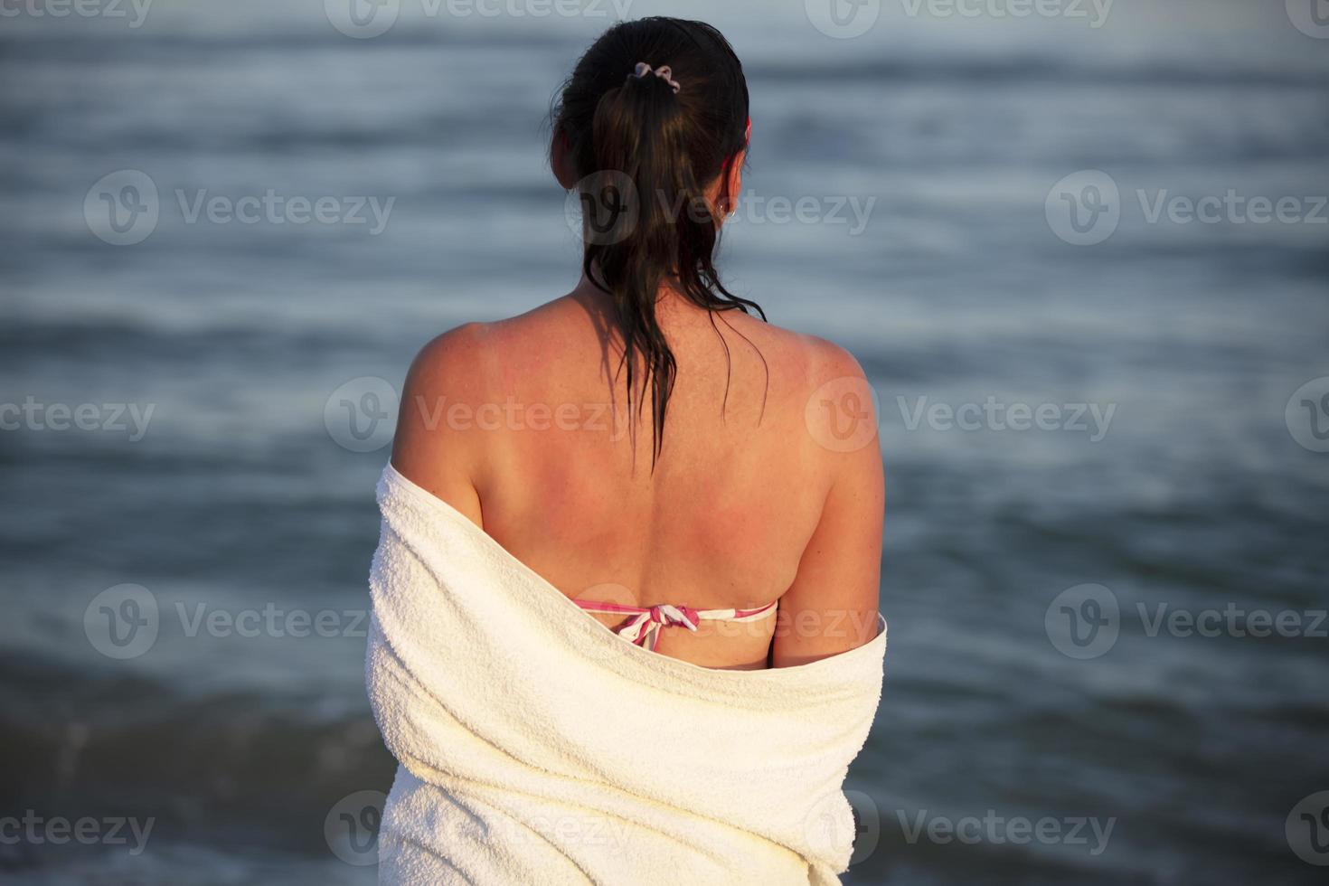 le femme des stands avec sa retour à le caméra et regards à le mer. photo