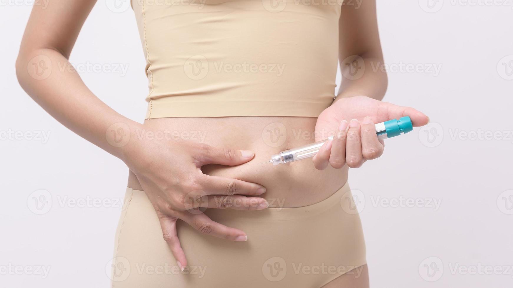 femme en gros plan utilisant une injection de traitement de fiv sur le ventre pour préparer la fertilité reproductive , la stimulation de l'ovulation . photo