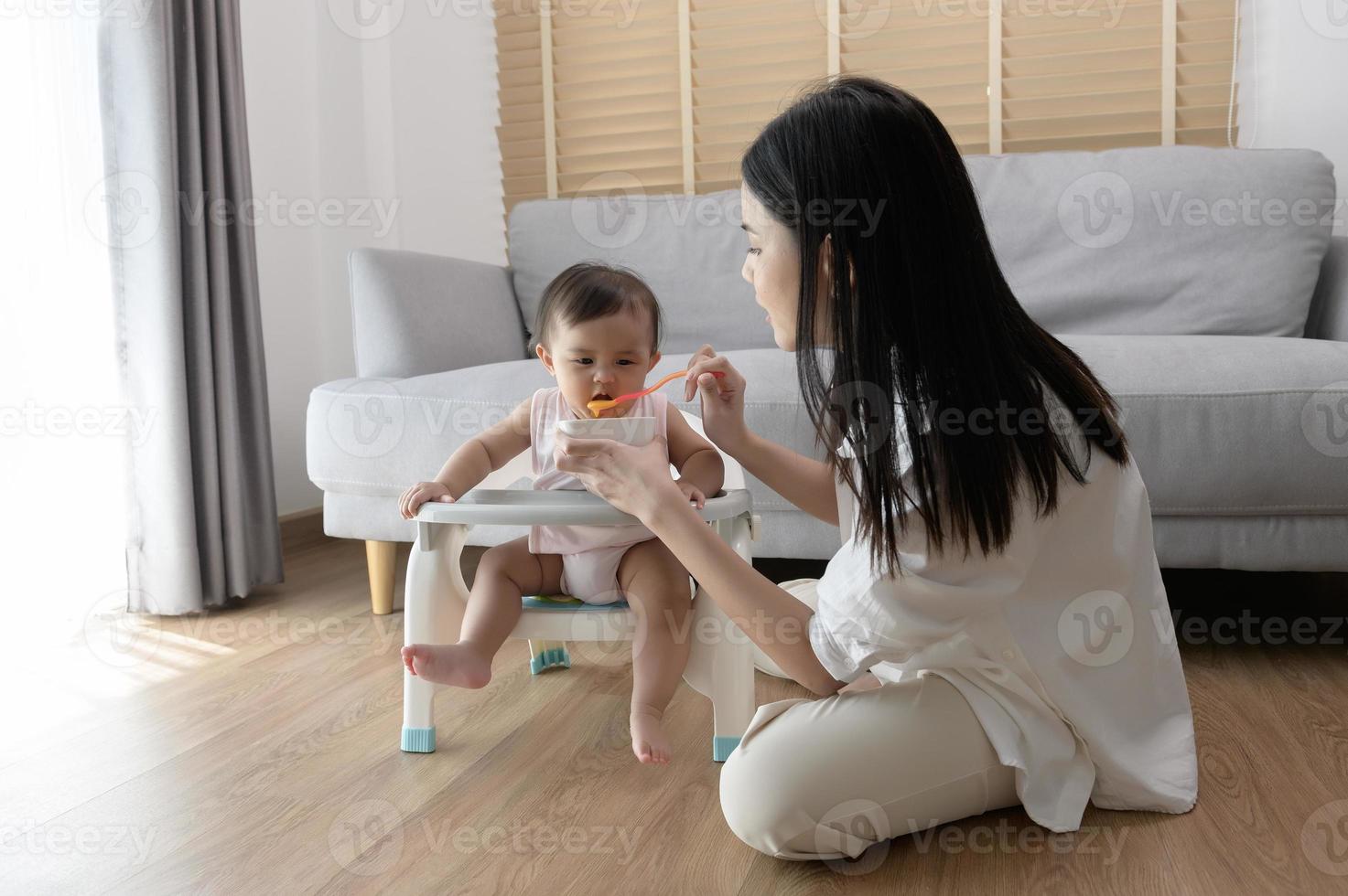 Jeune mère portion bébé en mangeant mélange nourriture sur bébé chaise  21697933 Photo de stock chez Vecteezy