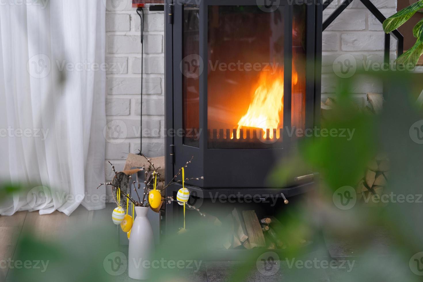 Pâques décor près cheminée le fourneau avec Feu et bois de chauffage. confortable Accueil foyer dans intérieur avec mis en pot des plans, coloré Pâques œufs, Pâques lapin et bouquet. printemps dans une pays maison photo