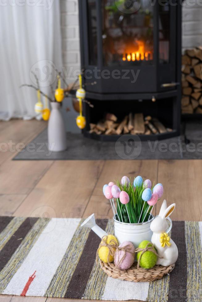 Pâques décor près cheminée le fourneau avec Feu et bois de chauffage. confortable Accueil foyer dans intérieur avec mis en pot des plans, coloré Pâques œufs, Pâques lapin et bouquet. printemps dans une pays maison photo