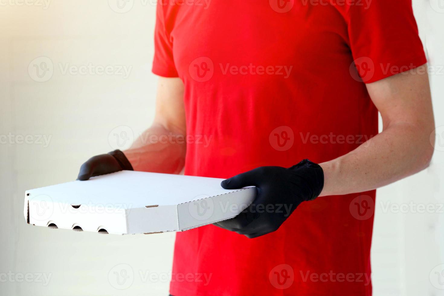 une homme mains caoutchouc gants avec une boîte Pizza . nourriture livraison pendant le quarantaine de le coronavirus pandémie. photo