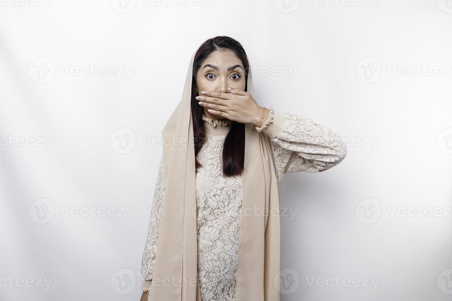 Oups surpris Jeune asiatique musulman femme couvrant bouche avec mains et regarder à caméra tandis que permanent contre blanc Contexte photo