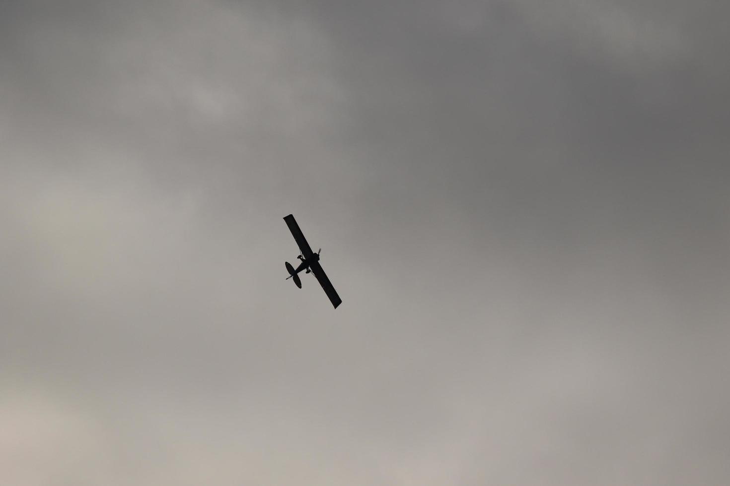 petit avion en volant dans le ciel contre foncé des nuages photo